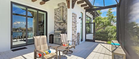 Un patio techado con mobiliario exterior, una parrilla y vistas del paisaje circundante.