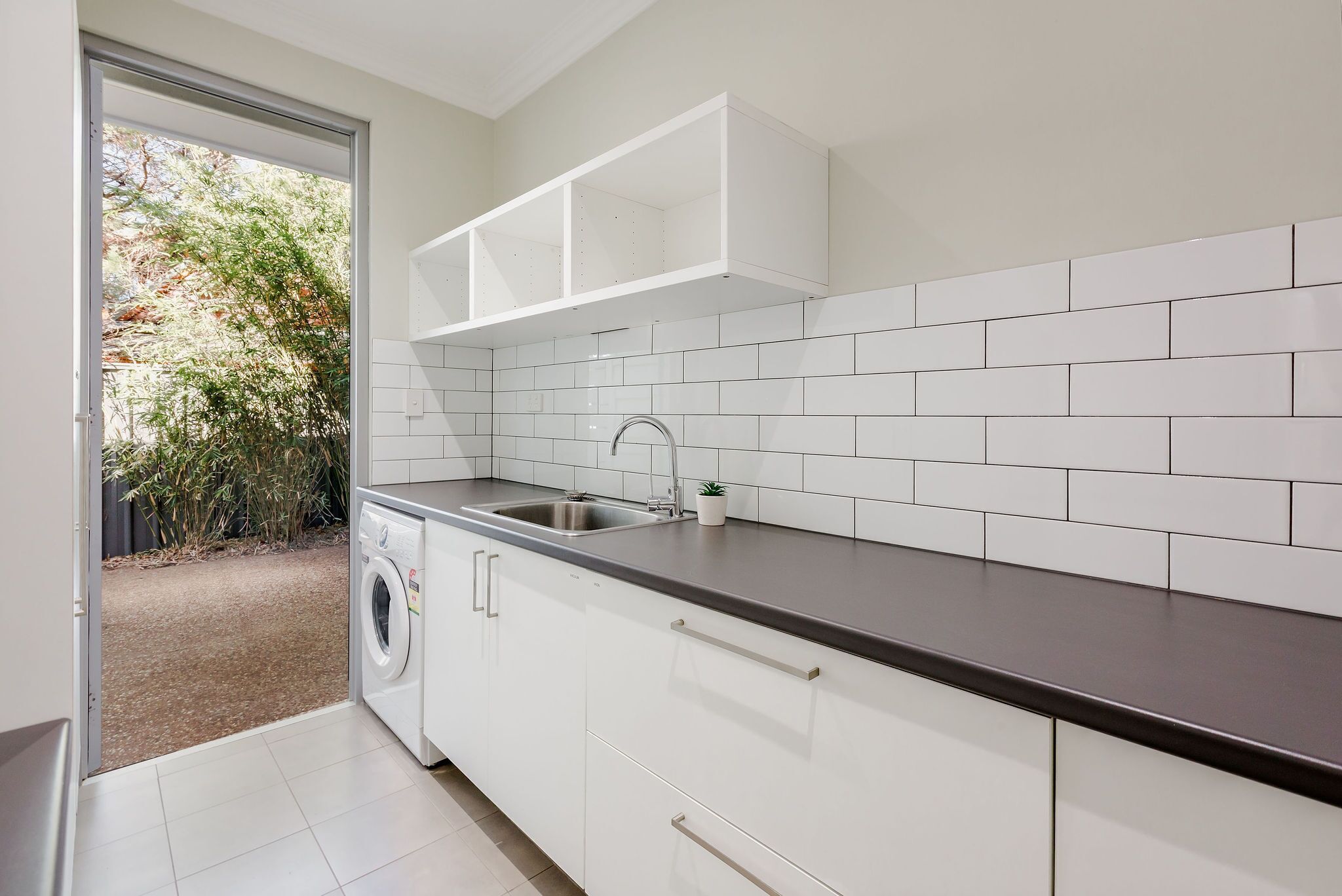 Een moderne keuken met witte kastjes, een donker aanrechtblad en een ingebouwd spoelbak.