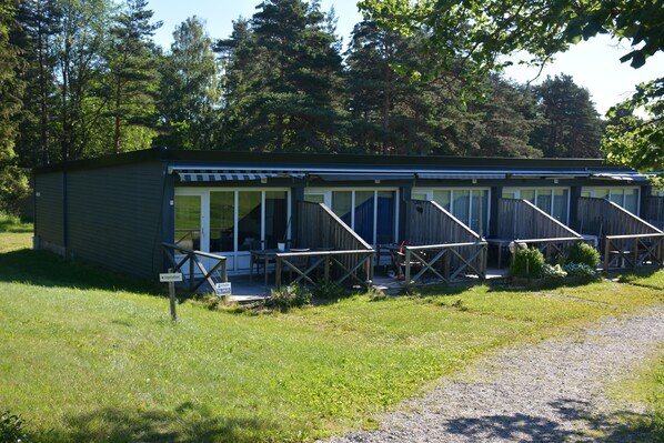 A small, single-story motel with a covered outdoor seating area and a gravel driveway.
