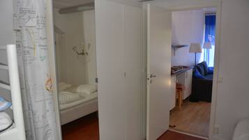 Una habitación con una cama, un escritorio y una silla. Hay una puerta que da a otra habitación.