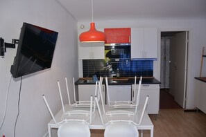 A modern kitchen with white cabinets, a red hanging light, and a built-in oven.