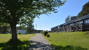 A gravel path leading to a row of wooden cabins with a tree on the left.