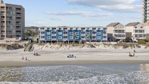 A beachfront hotel with multiple-story buildings, a sandy beach, and a clear sky. - Cozy, comfortable and freshly renovated oceanfront condo...you're gonna love it! (North Myrtle Beach)