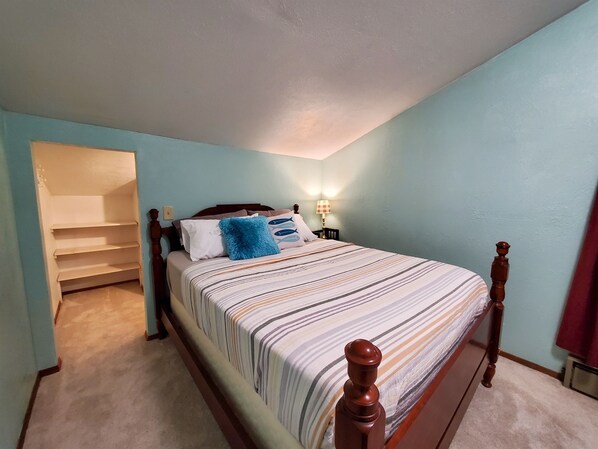 A bedroom with a bed, a nightstand, a lamp, and a built-in shelf.