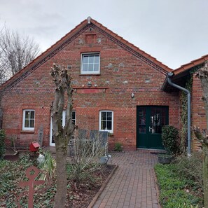 A brick building with a green door, a window, and a sign that reads "Moin". - Appartement Ottermeet (Ihlow)
