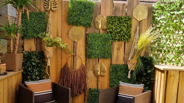 An outdoor patio with wicker furniture, a wooden deck, and various potted plants and decorative elements. - Appartement avec terrasse & parking Sarlat Centre (Sarlat-la-Canéda)