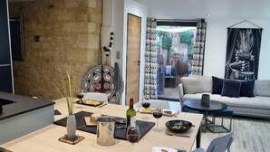 A modern dining area with a wooden table, chairs, and a view of the living room. - Appartement avec terrasse & parking Sarlat Centre (Sarlat-la-Canéda)