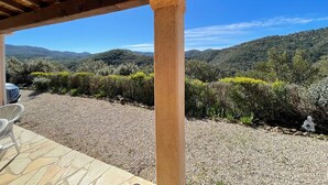 Eine überdachte Terrasse mit Blick auf eine gebirgige Landschaft.