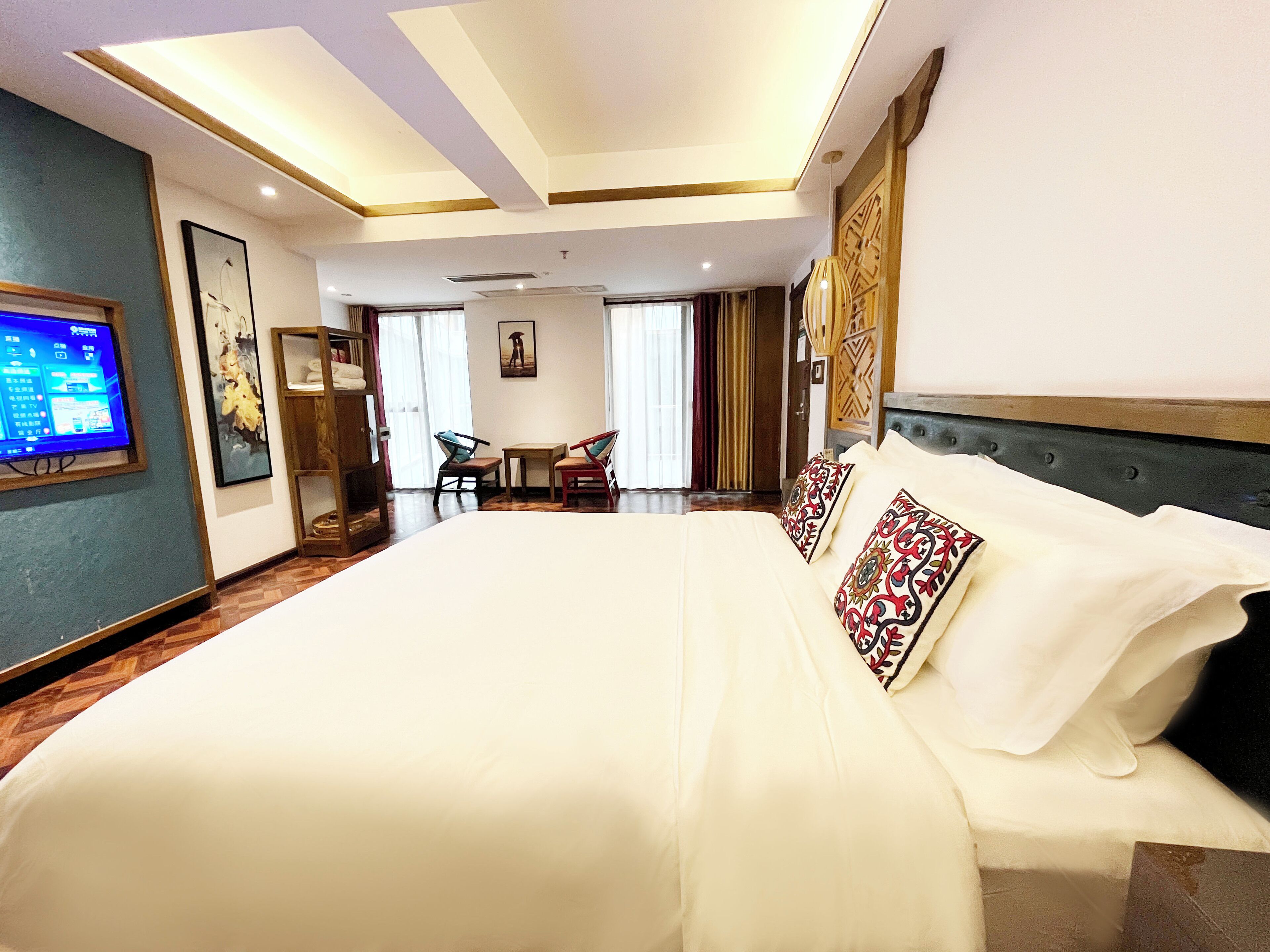 Une chambre d’hôtel avec un grand lit, un téléviseur sur le mur de gauche et un bureau avec des chaises.