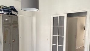 A room with a bed, a wardrobe, a door, and a hanging light fixture. - Appartement Terrasse (Armentières)