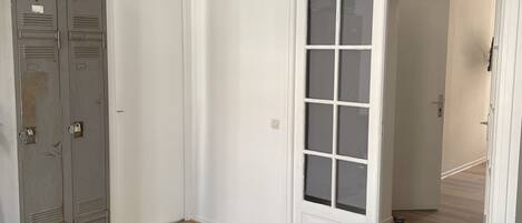 Ein Zimmer mit Bett, Kleiderschrank, Tür und einer Pendelleuchte.