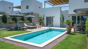 A modern outdoor pool area with lounge chairs, a stone wall, and a wooden pergola. - Modern Villa with Terrace View, Private Pool & BBQ (Rethymno)