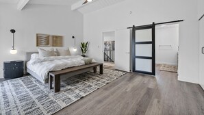 A bedroom with a bed, a bench, a ceiling fan, and a sliding door.