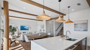 Een moderne keuken met een groot eiland, hanglampen en uitzicht op de woonkamer.