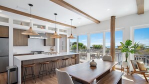 Een moderne keuken met een centraal eiland, barkrukken en een eettafel met banken.