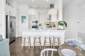 Una cocina moderna con armarios blancos, electrodomésticos de acero inoxidable y una isla central con taburetes de bar.