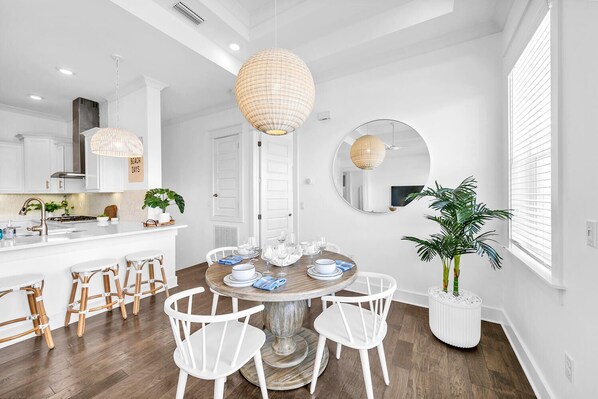 Una cocina moderna con armarios blancos, una isla central con taburetes e iluminación colgante.