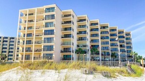 A multi-story hotel with balconies and large windows, located near a sandy beach. - Take Me A Wave 806–Ocean Views–Sleeps 4 (Panama City Beach)