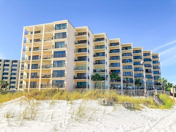 Ein mehrstöckiges Hotel mit Balkonen und großen Fenstern in Strandnähe.