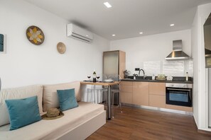 A modern kitchen with a dining area, a built-in oven, and a large window. - Nieva Apartment 2 (Matala)