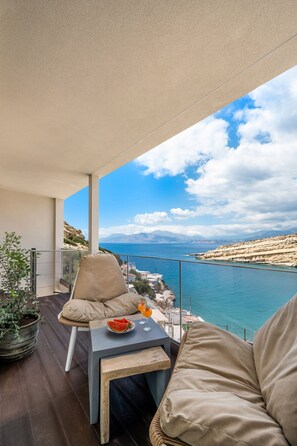 Un balcone con vista sul mare, un tavolo con una ciotola di frutta e una sedia.