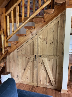 A wooden staircase with a rustic design, leading to a room with a large wooden wardrobe.