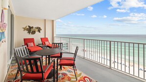 Un balcón con una mesa y sillas, vista a la playa y barandilla.