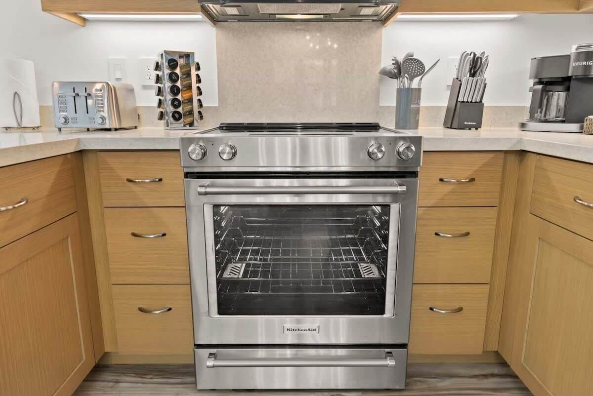 Eine moderne Küche mit Backofen aus Edelstahl, Holzschränken und einer Kaffeemaschine.