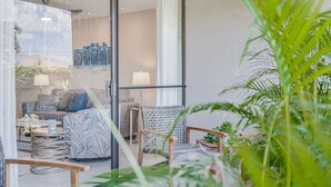 Un soggiorno moderno con una porta in vetro che dà su un balcone, arredato con un divano, poltrone e un tavolino.