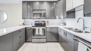Una cucina moderna con elettrodomestici in acciaio inossidabile, mobili grigi e un piano di lavoro bianco.