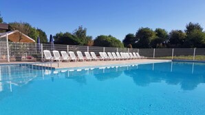 A swimming pool with white lounge chairs and a fence. - Giuliott with parking and shared pool by Interhome (De Haan)