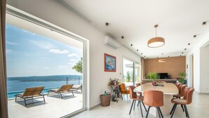 A modern dining area with a large table and chairs, a view of the sea, and a large window. - Villa Murn by Interhome (Crikvenica)