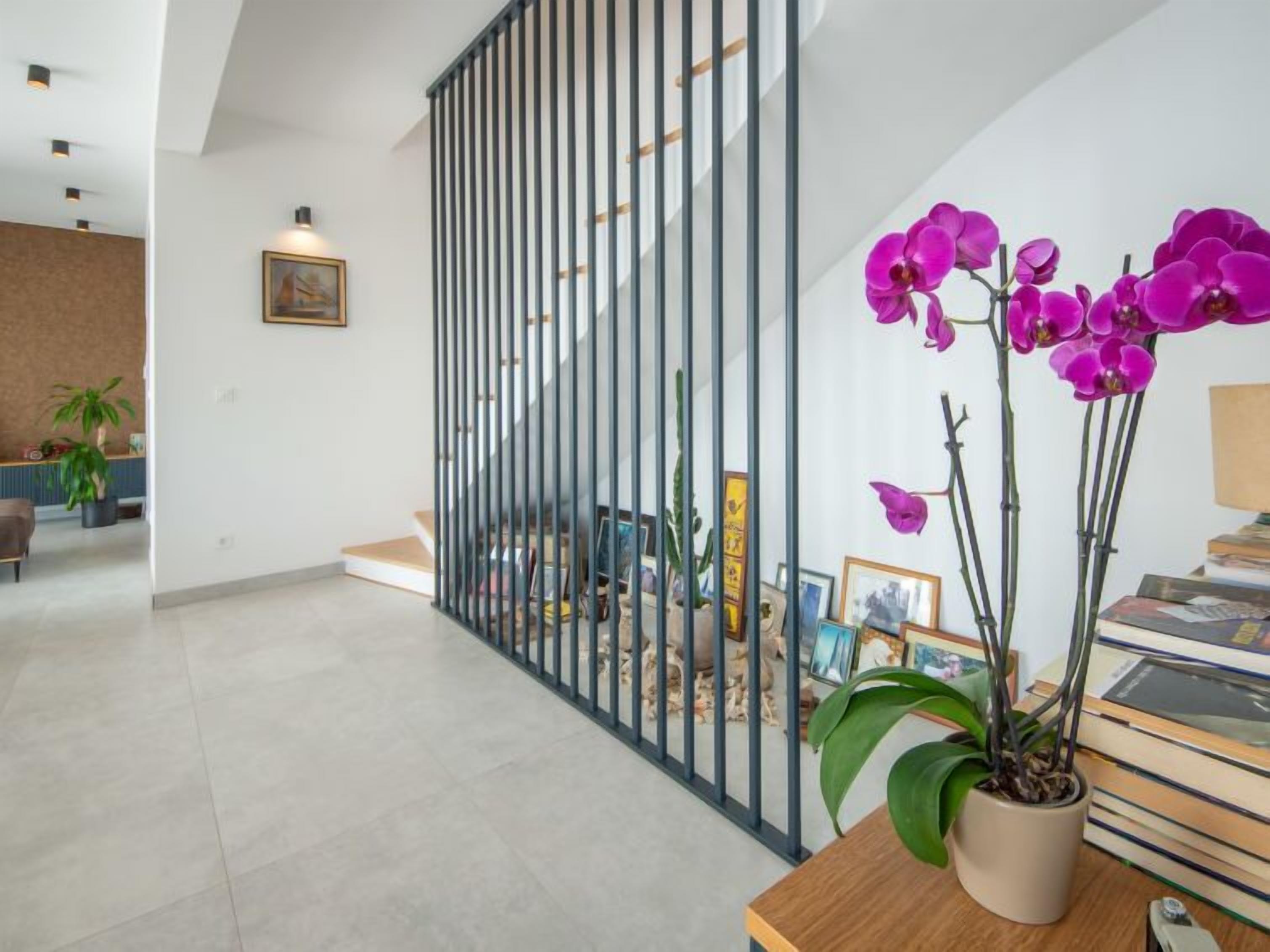 Ein modernes Interieur mit Treppe, einer Topf-Orchidee und einem Schreibtisch mit Büchern.