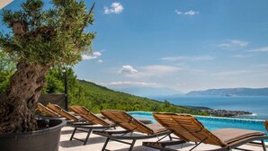 A poolside area with lounge chairs and a large potted tree. - Villa Murn by Interhome (Crikvenica)