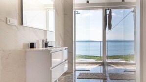 A modern bathroom with a marble vanity, a glass shower enclosure, and a view of the sea. - Villa Murn by Interhome (Crikvenica)