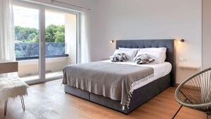 Un dormitorio moderno con una cama grande, una silla y vistas a zonas verdes.