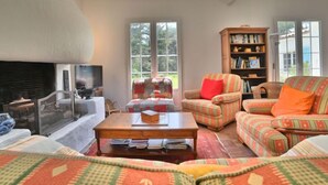 Un salon chaleureux avec une cheminée, un canapé, un fauteuil, une table basse et une bibliothèque.