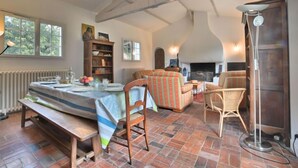 Un vaste espace de vie agrémenté d’une cheminée, d’une table à manger pour quatre personnes et d’un coin salon confortable.