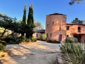 A building with a circular tower, a balcony, and a gravel driveway.