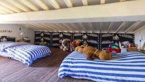 A bedroom with two beds, striped bedding, a wall tapestry, and stuffed animals. - La Tourelle des Ocres by Interhome (Roussillon)
