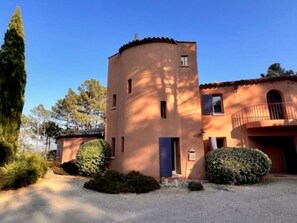 Un bâtiment à deux étages, doté d’une tour circulaire, d’un balcon et d’une allée gravillonnée.