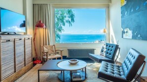 Una sala de estar moderna con un ventanal que ofrece vistas al océano, un televisor y un rincón de descanso acogedor.