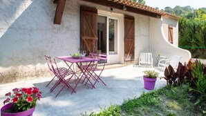 Un patio con tavolo e sedie, una pianta in vaso e una sedia bianca.