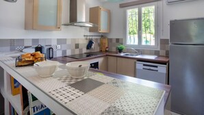 Una cucina moderna con isola centrale, elettrodomestici in acciaio inossidabile e una finestra vista su spazi verdi.