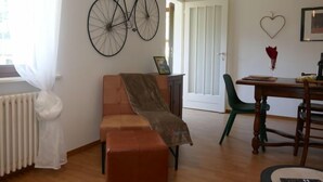 A cozy living room with a sofa, a dining table, and a bicycle mounted on the wall. - Apartment Lara by Interhome (Olivone)