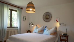 A bedroom with a large bed, a hanging lamp, a wall clock, and a radiator. - Apartment Lara by Interhome (Olivone)