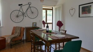 A dining area with a wooden table, chairs, and a bicycle decoration on the wall. - Apartment Lara by Interhome (Olivone)