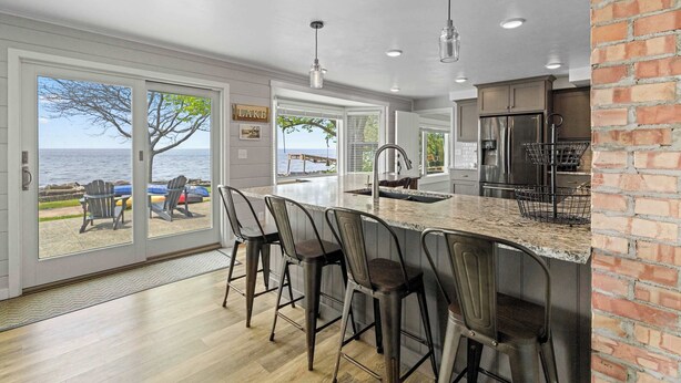 A kitchen with a large island, bar stools, a refrigerator, and a view of the sea. - Egg Harbor home with waterfront access-Sleeps 12! (Egg Harbor)