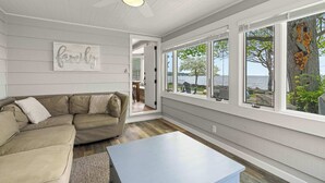 A living room with a beige sectional sofa, a white coffee table, and a ceiling fan. - Egg Harbor home with waterfront access-Sleeps 12! (Egg Harbor)