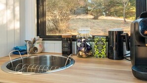 A kitchen counter with a sink, a coffee maker, a jar of tea bags, and a box of green tea. - Blue Gum at Langdale 1 by Tiny Away (Bungendore)